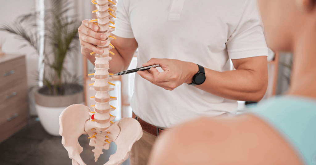 chiropractor educating patient while using a model of a spine
